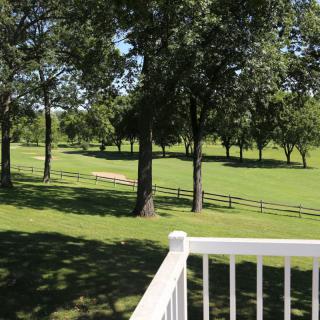 A serene view of a green park with trees and a wooden fence.