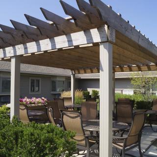 A sunny outdoor patio with a pergola and comfortable seating arrangement.