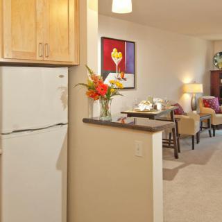 A cozy open floor plan showcasing a kitchen with wooden cabinets and adjacent living area adorned with colorful artwork and furniture.