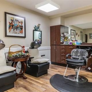 A cozy hair salon interior with chairs, mirrors, and hair drying equipment.