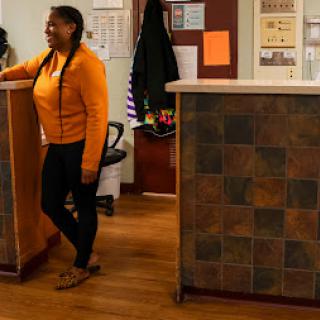 A welcoming interior space with a person in casual attire standing by a reception desk.