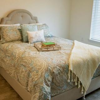 A cozy bedroom with a neatly made bed adorned with decorative pillows and a textured blanket.