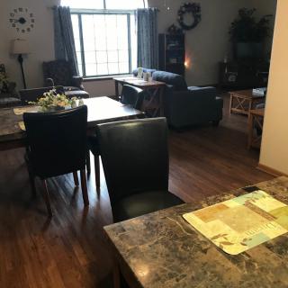 A cozy living and dining area with a window, tables and chairs, and a sofa on wood flooring.