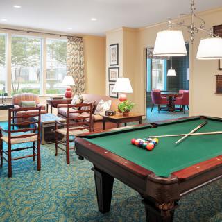 A cozy game room featuring a pool table, comfortable seating, and ambient lighting.