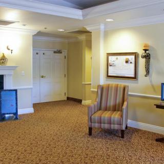 A cozy lobby area with a striped chair and a decorative fireplace.