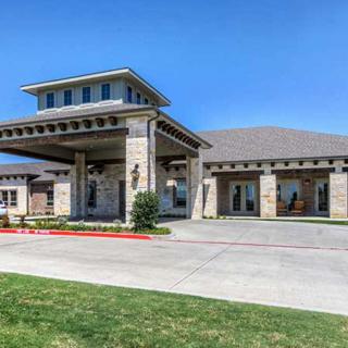 A modern building featuring a large covered entrance and driveway under a clear blue sky.