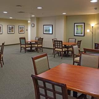 A spacious dining area with multiple tables and chairs, decorated with wall art and softly lit by lamps.