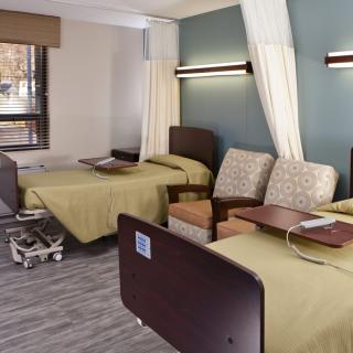 A hospital room with two beds and seating area.