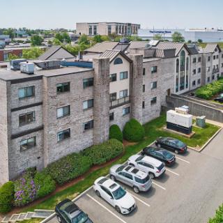 Aerial view of a modern apartment building with a parking lot and landscaped surroundings.