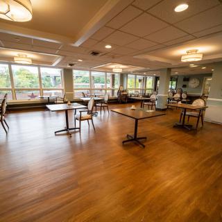 A spacious dining area with wooden flooring and large windows.