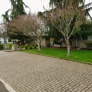 Suburban house with a paved driveway and surrounding trees.