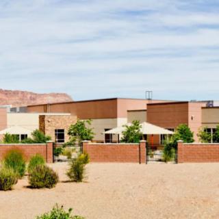 Modern desert home with brick walls and outdoor seating under a clear blue sky.