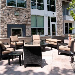 A modern outdoor patio with cushioned seating and a stone wall backdrop.