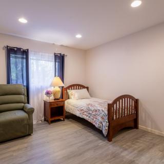 A cozy bedroom with a single bed and recliner chair, featuring minimalist decor.