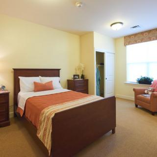 A cozy and well-furnished bedroom with a bed, dresser, and armchair.