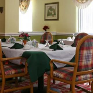 A cozy dining area with elegantly set tables and plaid-patterned chairs.