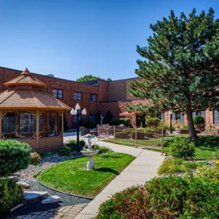 A beautifully landscaped garden with a gazebo and a brick building in the background.