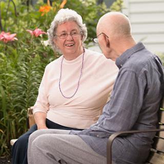 An elderly couple enjoys a warm conversation in a beautiful garden.