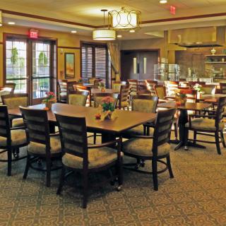 An elegant dining area with neatly arranged tables and chairs, featuring warm lighting and decor.