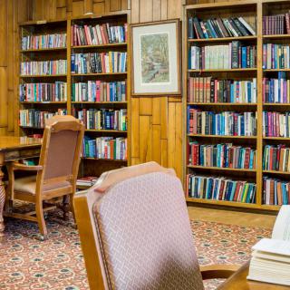A cozy library reading room with wooden bookshelves filled with books and comfortable seating.