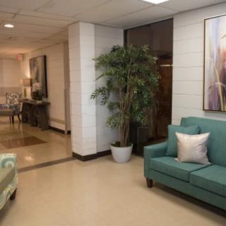A cozy lobby area featuring teal couches, a potted plant, and framed artwork on the walls.