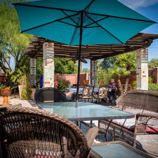 A sunny outdoor patio area with wicker furniture and a blue umbrella.