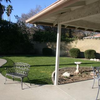 A sunny backyard with a patio, outdoor furniture, and well-maintained landscaping.