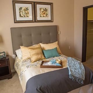 A cozy bedroom with a neatly made bed, decorative pillows, and framed artwork on the wall.