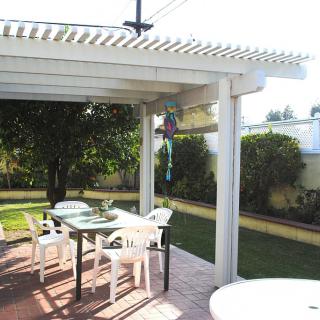 A sunny patio with a pergola, outdoor furniture, and a lush garden.