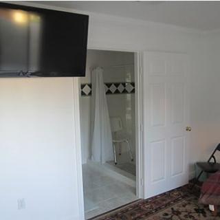 A modern hotel room featuring a wall-mounted television and an open bathroom entry.