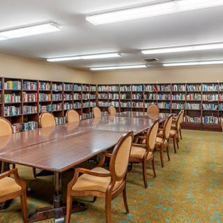 A library meeting room with a long table surrounded by chairs and walls lined with bookshelves.