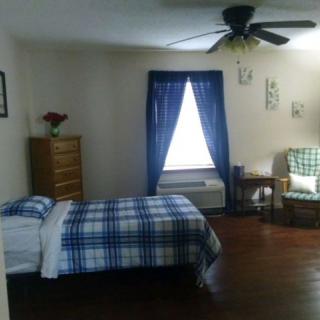 A cozy bedroom with a single bed featuring blue checkered bedding,
complemented by matching curtains and a wooden dresser.