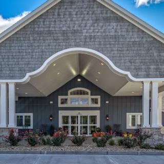 The charming entrance of a modern architectural building, featuring elegant design and vibrant landscaping.