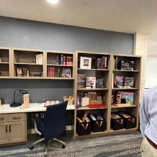 A modern office workspace featuring bookshelves filled with books and decorative items, alongside a neatly arranged desk and chair.