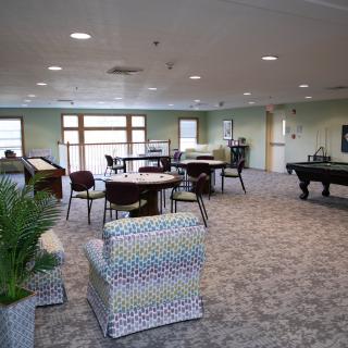 A spacious lounge room featuring comfortable seating, tables, and a pool table for relaxation and recreation.