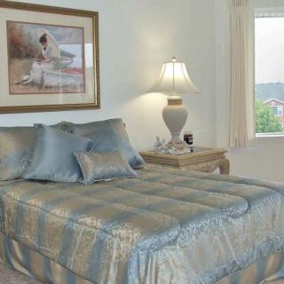 A cozy bedroom with a neatly made bed, decorative pillows, and a bedside lamp.