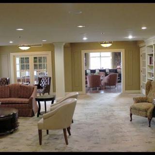 A spacious living room with a traditional decor style, featuring comfortable seating and built-in bookshelves.