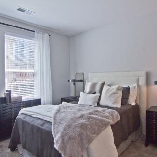 A cozy and well-decorated bedroom with a neatly made bed, featuring soft pillows and a plush blanket.