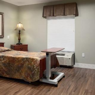 A hospital room with a bed, nightstand, and lamp.