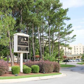 A hotel entrance with signs, surrounded by trees and well-maintained landscaping.