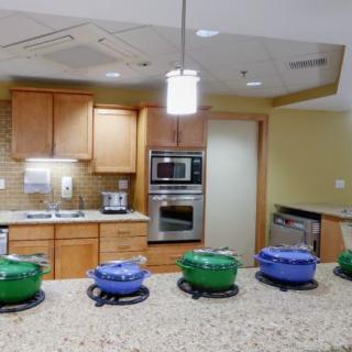 A modern kitchen with a row of colorful cookware on the countertop.