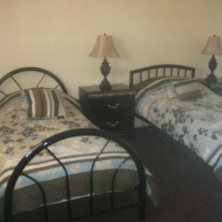 A cozy bedroom featuring twin beds with decorative linens and a shared nightstand with lamps.