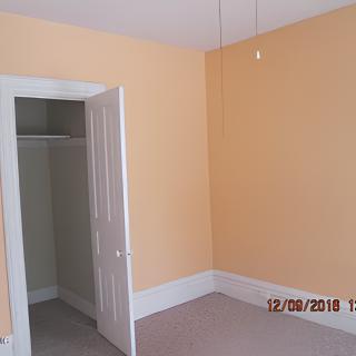 An empty room with peach-colored walls and a closet with an open door.