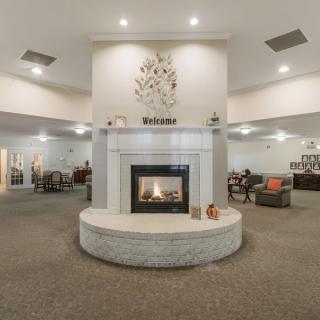 A spacious and elegant lobby interior featuring a central fireplace with surrounding seating areas.
