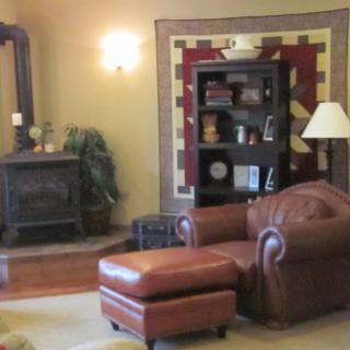 A cozy living room with a leather chair, wood stove, and bookshelf.