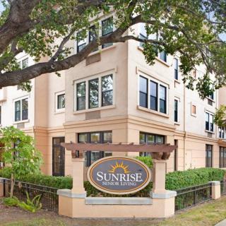 A residential apartment building with a sign in front labeled 'Sunrise'.