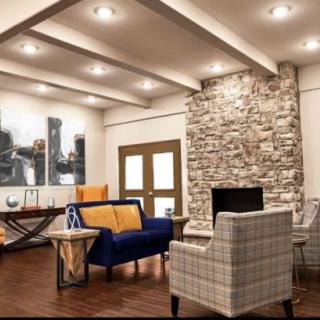 A modern living room with a stone fireplace, stylish furniture, and wood flooring.