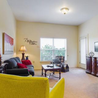 A cozy living room with a sofa, armchair, and coffee table, illuminated by natural light from the window.