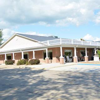 A brick building with a paved parking area under a partly cloudy sky.