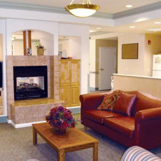 A cozy living room featuring a leather sofa, central fireplace, and a wooden coffee table with floral centerpiece.